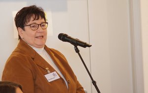Eine kurzhaarige Frau mit Brille spricht in ein Mikrofon