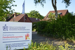 Im Vordergrund ein Hinweisschild, im Hintergrund Gebäude